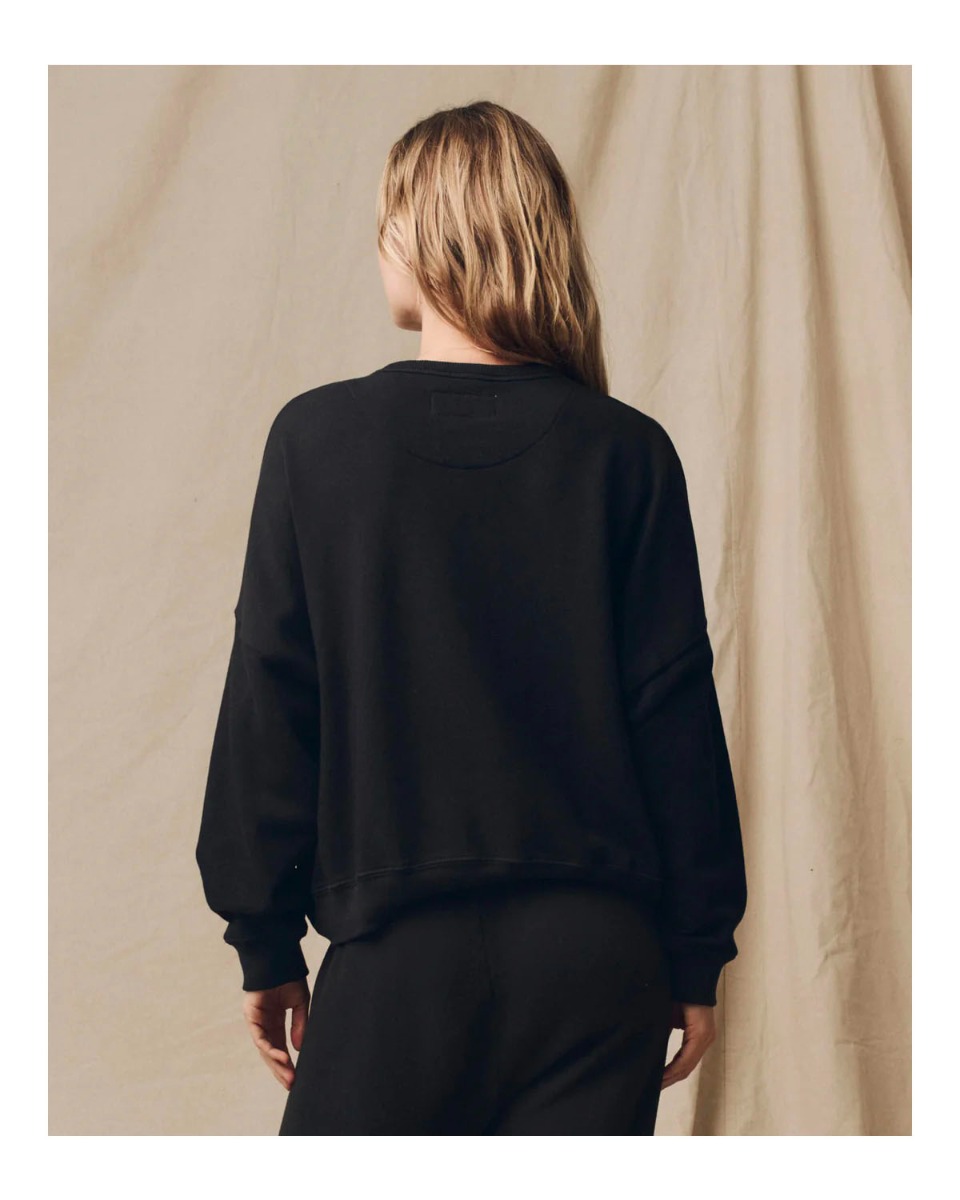 Sweatshirt Teammate en coton noir The Great. Porté de dos avec un bas de jogging assorti. 