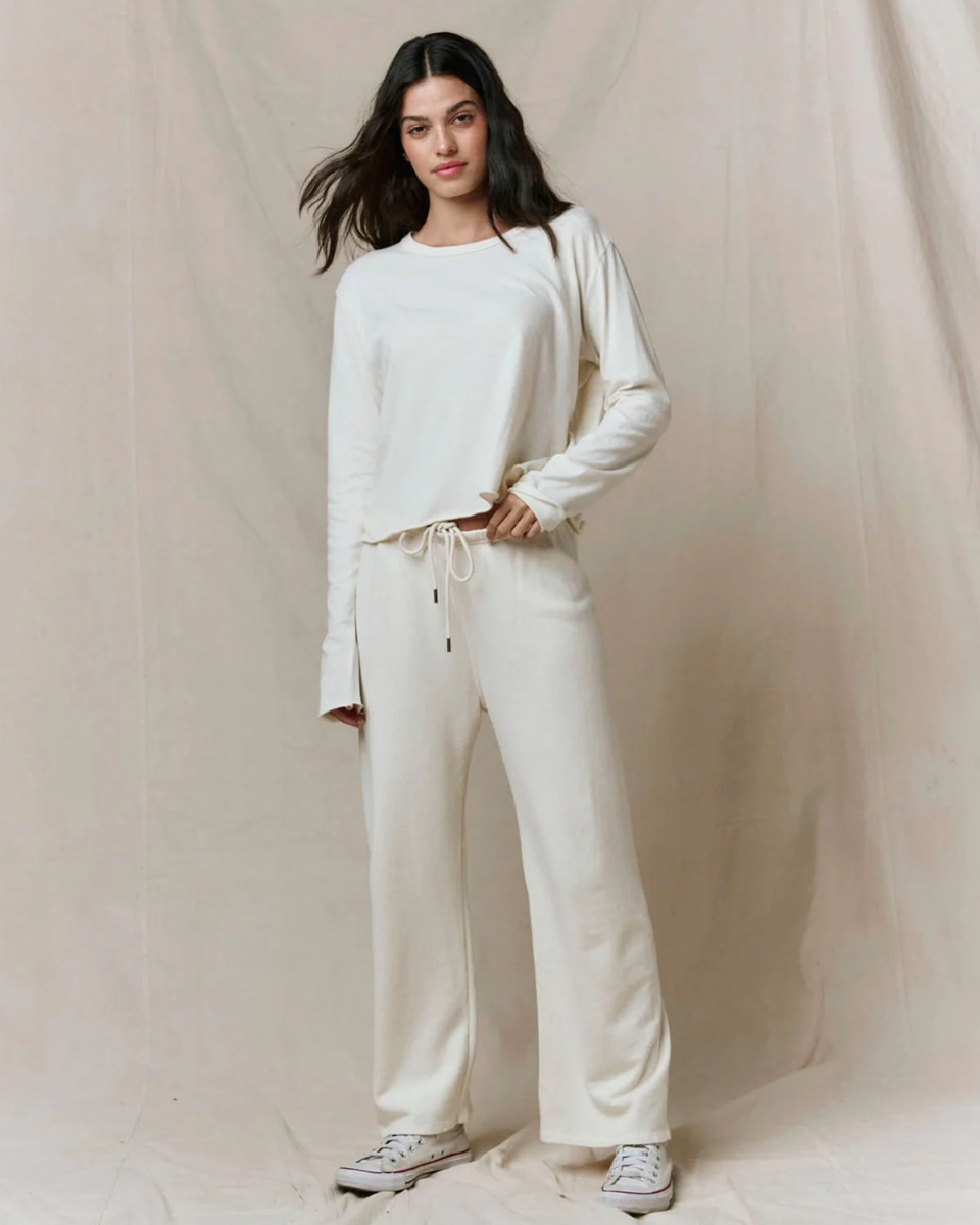 Tee-shirt manches longues Crop The Great en coton &eacute;cru, port&eacute; de face avec un bas de jogging assorti.