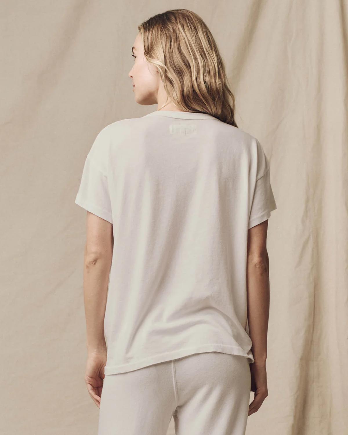Tee-shirt en coton écru The Boxy Crew de The Great, porté de dos avec un bas de jogging décontracté pour un look effortless.
