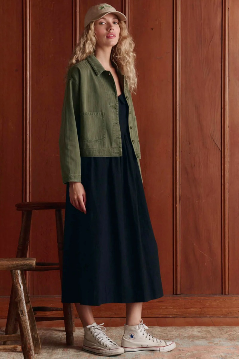 Veste de travail vintage Rancher The Great en coton kaki, port&eacute;e de profil avec une robe longue noire.