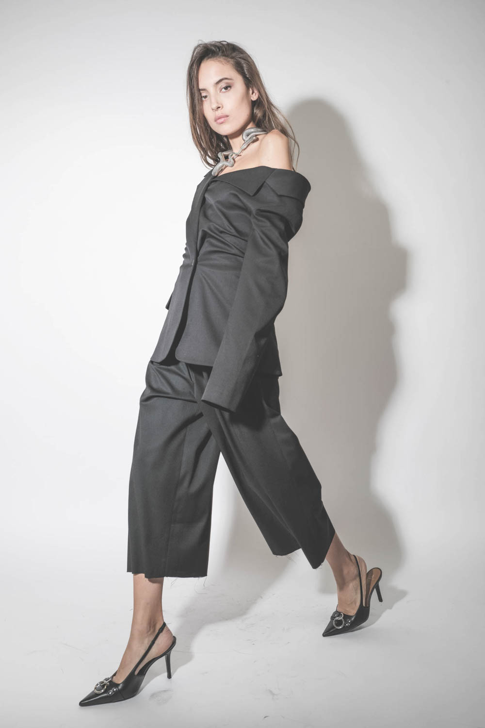 Blazer asymétrique en laine froide noire Anissa Vautrait. Porté de profil.