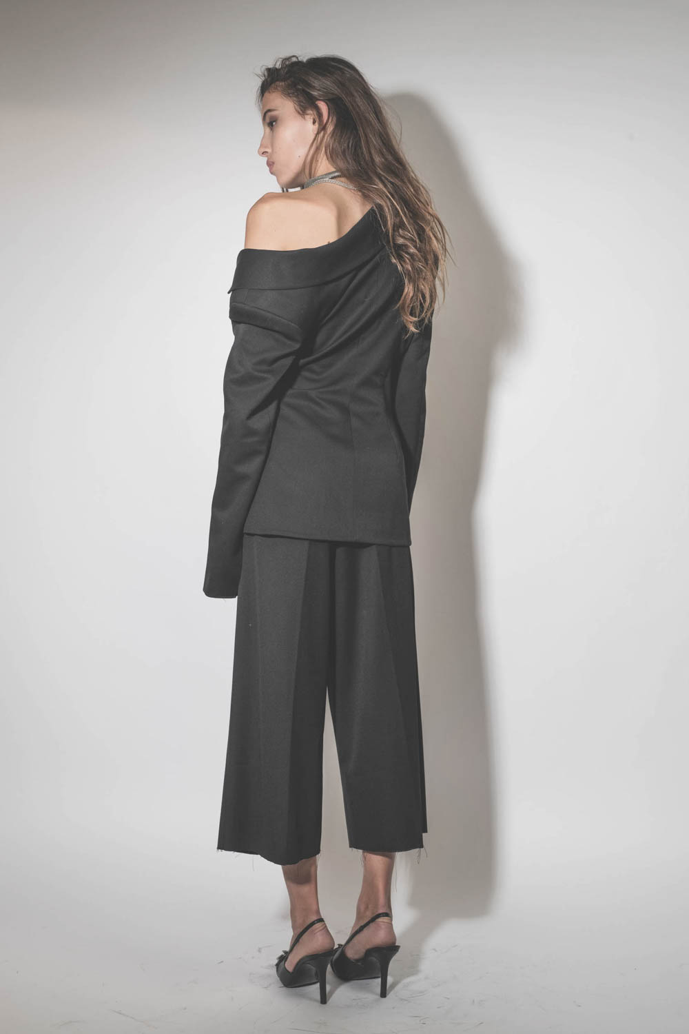 Blazer asymétrique en laine froide noire Anissa Vautrait. Porté de dos.