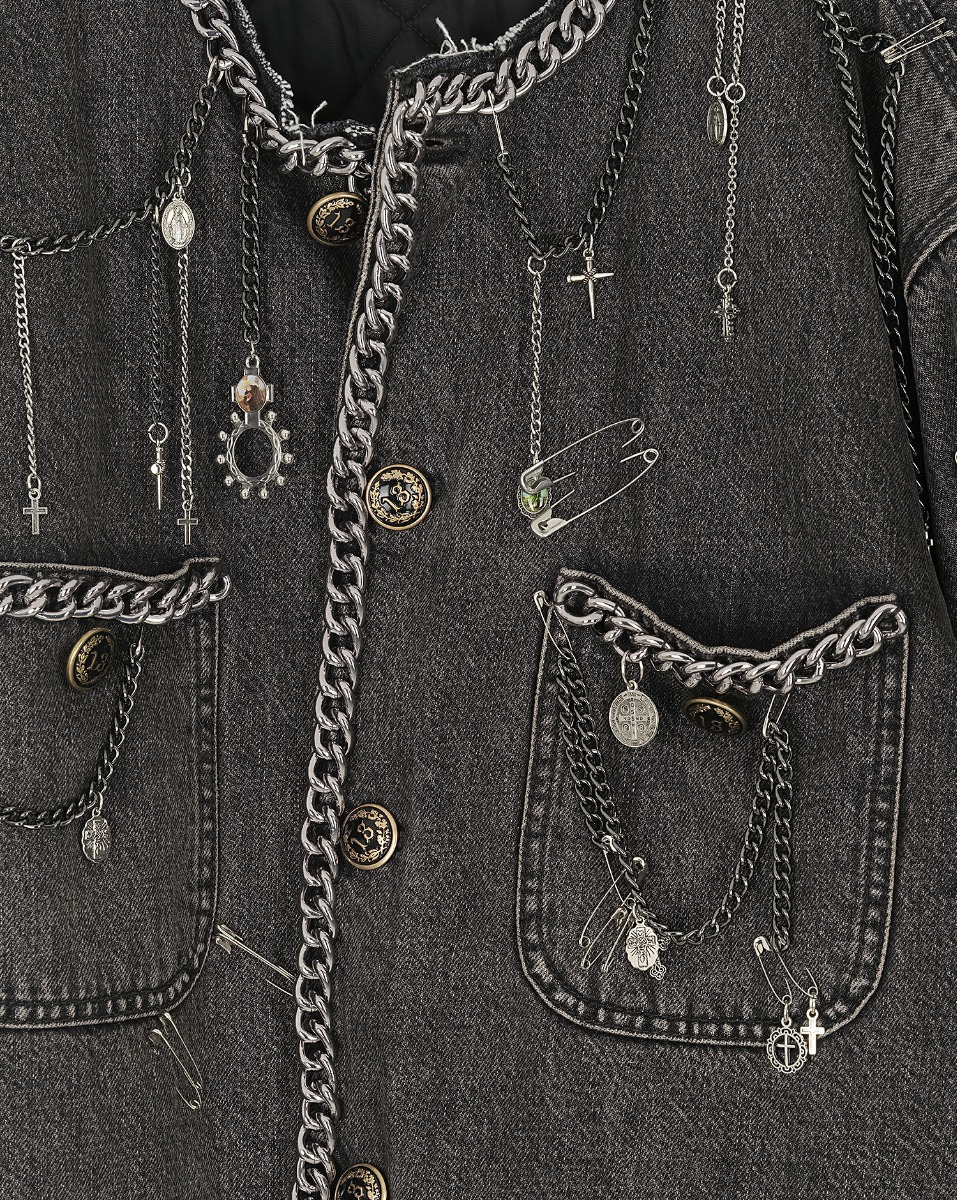 Veste courte Chain Embellished Cropped Chore Jacket R13 en denim gris foncé, customisée avec des chaînes, des épingles à nourrice et des médailles en argent. Détail des bijoux.