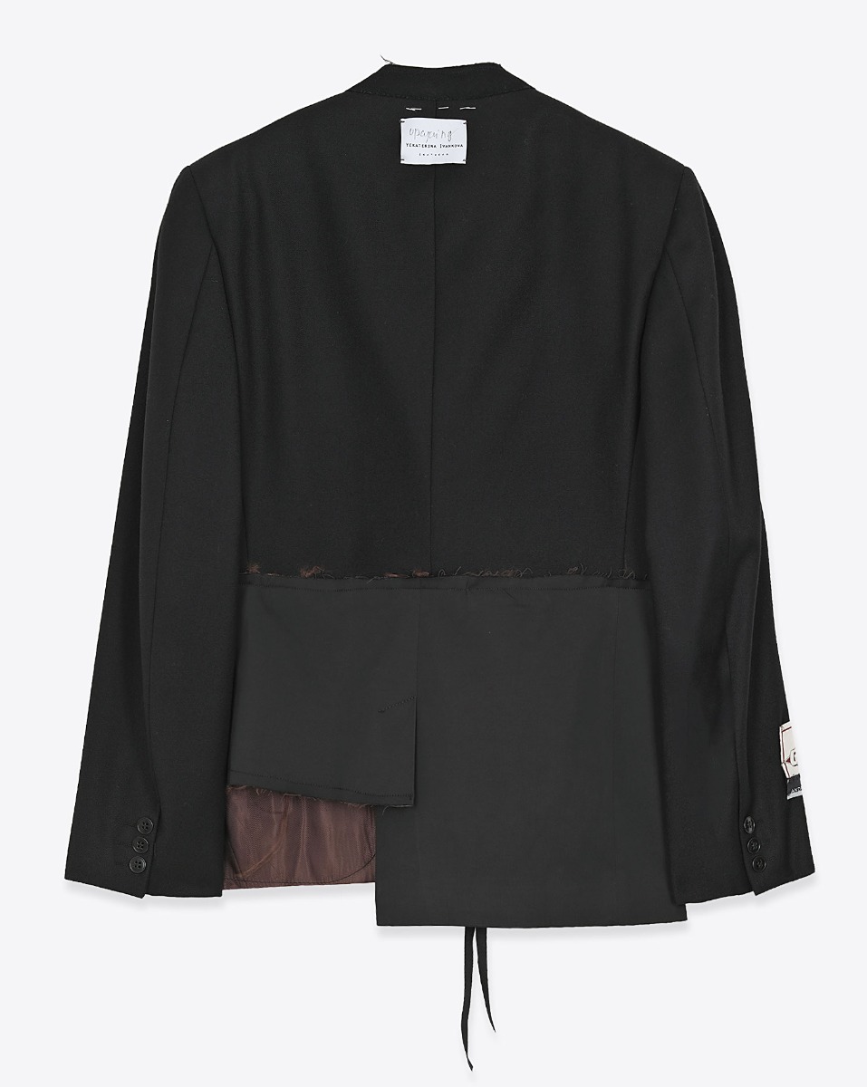 Blazer customis&eacute; par Yekaterina Ivankova Upcycling en laine vierge noir. D&eacute;tail du bas avec un c&ocirc;t&eacute; plus court que l'autre. Vue de dos.